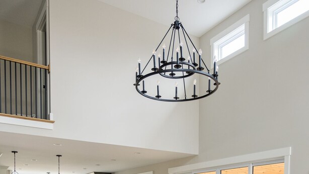 Un salon spacieux avec un canapé d’angle gris, un lustre et une vue sur l’extérieur.