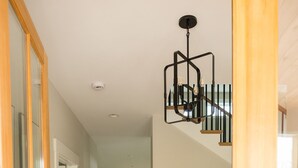 Un escalier en bois avec une rampe en métal noir et un luminaire moderne.