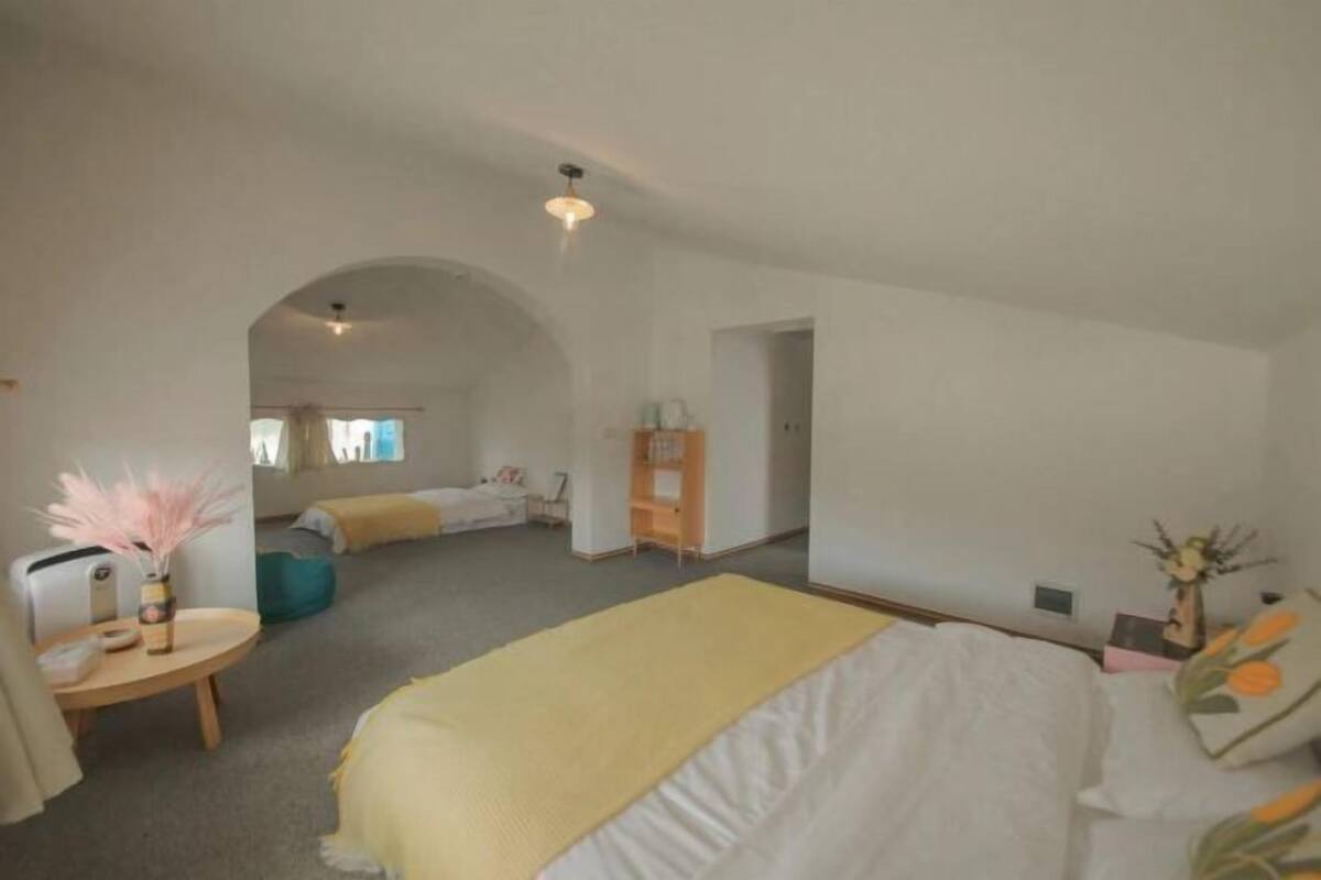 Ein Schlafzimmer mit Bett, Schreibtisch, Stuhl, Kleiderschrank und einer kleinen Sitzecke.