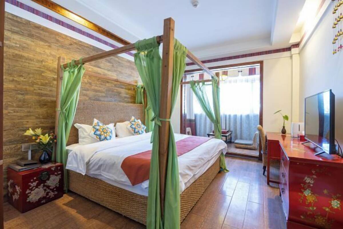 Ein Zimmer mit einem Himmelbett, einem Fernseher, einem Schreibtisch und einem roten Schrank.