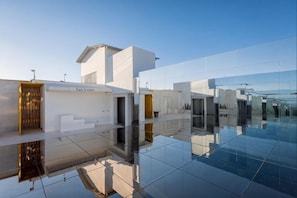 Un bĂątiment moderne dotĂ© dâun sol en verre rĂ©flĂ©chissant, dâun toit plat et dâun design minimaliste.
