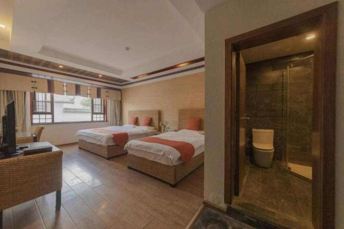 Ein Hotelzimmer mit zwei Betten, einem Schreibtisch und einem Badezimmer mit Toilette und Waschbecken.