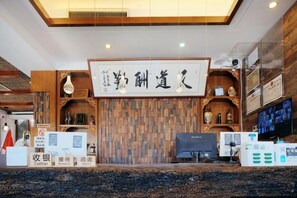 A reception area with a wooden wall, a cash register, and a computer. - Langyue Hanfu Travel Theme Inn (Lijiang Ancient City Branch) (Lijiang)