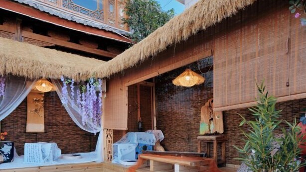 A traditional wooden building with a thatched roof, a wooden bench, and a small table. - Langyue Hanfu Travel Theme Inn (Lijiang Ancient City Branch) (Lijiang)