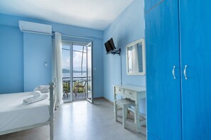 Un dormitorio con cama, escritorio, armario y balcón con vistas.