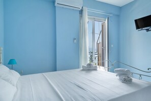 Ein Hotelzimmer mit Bett, Fernseher und einem Fenster mit Vorhängen.