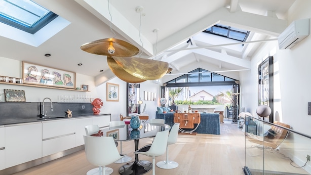 A modern kitchen with a glass dining area, a large pendant light, and a view of the outdoors.
