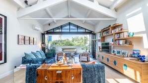 A spacious living area with a high ceiling, a built-in bookshelf, and a comfortable seating arrangement.