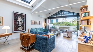 A spacious living room with a high ceiling, a large window, and a cozy seating area.