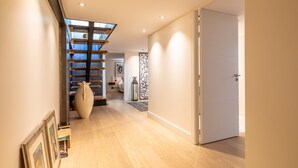A modern interior with a wooden staircase, a large vase, and a door leading to another room.