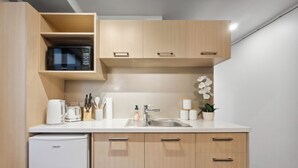 Une cuisine compacte équipée d’un four à micro-ondes encastré, d’un évier et d’un réfrigérateur.