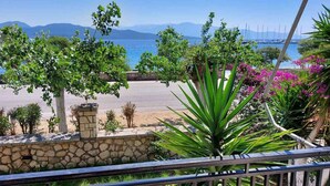 A balcony with a view of a beach, a stone wall, and various plants. - Room 'Double  Mountain View 5' with Mountain View, Wi-Fi and Air Conditioning (Nikiana)