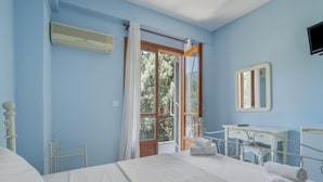 A bedroom with a bed, a bedside table, a mirror, and a window with curtains. - Room 'Double  Mountain View 5' with Mountain View, Wi-Fi and Air Conditioning (Nikiana)