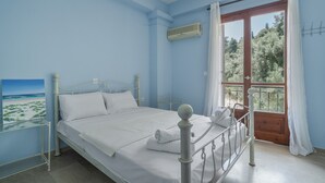 A bedroom with a bed, a window with curtains, a painting on the wall, and a balcony door. - Room 'Double  Mountain View 5' with Mountain View, Wi-Fi and Air Conditioning (Nikiana)