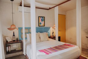 A bedroom with a canopy bed, a blue headboard, a bedside table with a lamp, and a wall-mounted air conditioner. - LUúM, A WELL-LOCATED OASIS, IDEAL FOR RECONNECTING WITH NATURE. (Mérida)