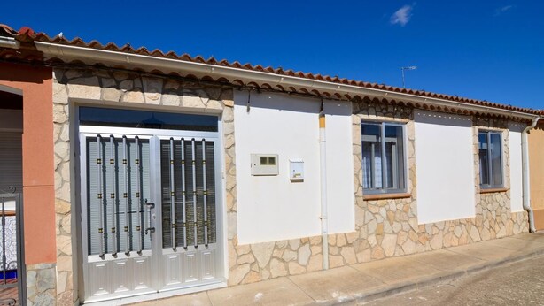 A two-story building with a stone facade, a metal gate, and a small window. - Brother's Village (Villardefrades)