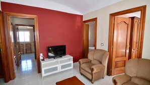 A living room with a TV on a white cabinet, two armchairs, and a wooden coffee table. - Brother's Village (Villardefrades)