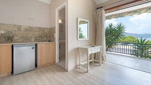 A kitchen with a dishwasher, a white desk, and a view of the sea.