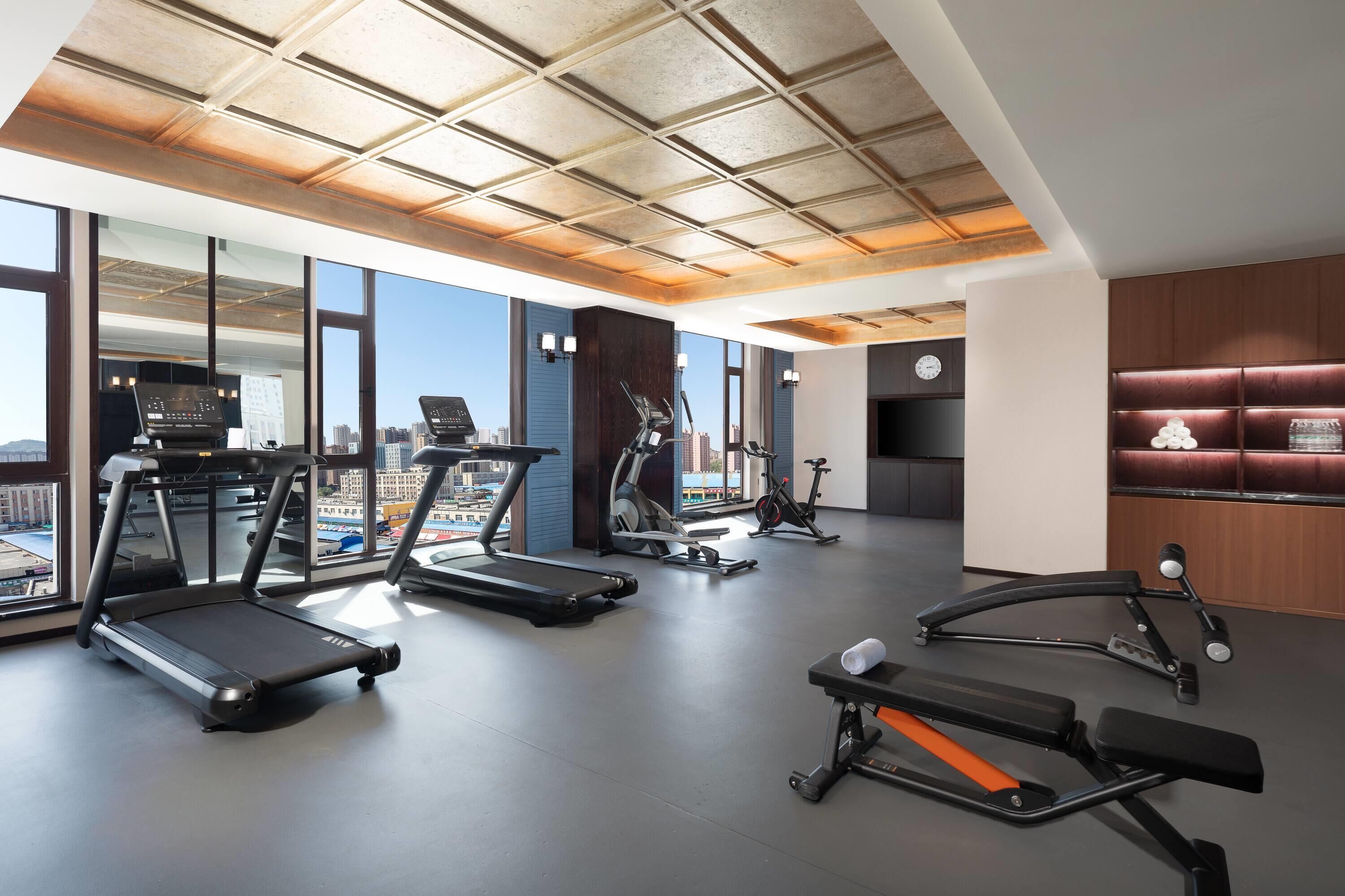 A modern gym with treadmills, elliptical machines, and weight benches.