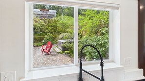 A room with a large window overlooking a garden and a house.