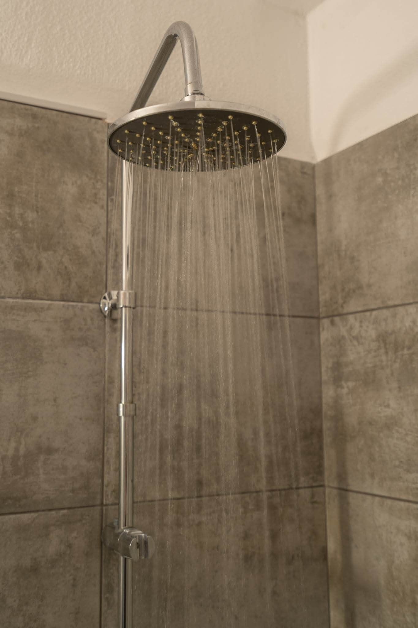 A shower with a curved head and multiple water jets.