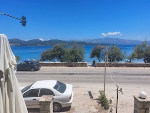 Une route côtière, avec une voiture blanche garée sur le bord, un lampadaire et un panneau indicateur.