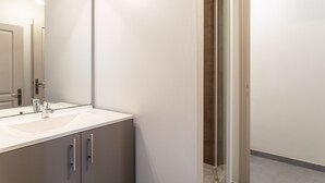 A modern bathroom with a large mirror, a sink, and a shower area.