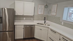 Une cuisine moderne dotée d’appareils électroménagers en acier inoxydable, de meubles blancs et d’un dosseret décoré d’un motif en chevrons.