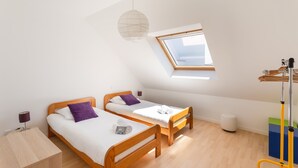 Ein Zimmer mit zwei Holzbett, einem Oberlicht, einer weißen Deckenleuchte und einem Holzboden.