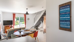 Ein Essbereich mit einem Holztisch, Stühlen und einem Fernseher. Im Hintergrund ist eine Treppe zu sehen.