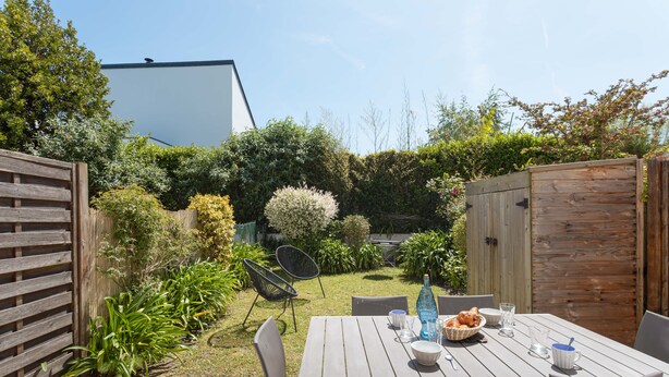 Eine Terrasse mit einem Esstisch, umgeben von Holzzäunen und verschiedenen Pflanzen.