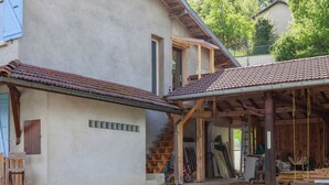 A rustic house with a covered porch, a wooden staircase, and various construction materials.