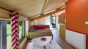 A cozy bedroom with a bed, a small table, and a view of the outdoors.