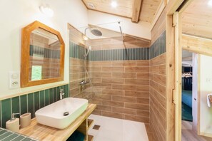 A modern bathroom with a wooden vanity, a large mirror, and a shower area.