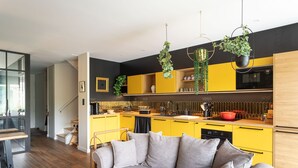 A modern kitchen with yellow cabinets, a grey sofa, and hanging plants. - La Petite Mare - proche de Rennes (Saint-Jacques-de-la-Lande)