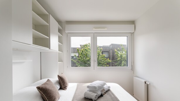 A modern hotel room with a large bed, white walls, and a view of trees through a window. - La Petite Mare - proche de Rennes (Saint-Jacques-de-la-Lande)