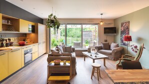 A modern kitchen with yellow cabinets, a wooden dining table, and a sofa. - La Petite Mare - proche de Rennes (Saint-Jacques-de-la-Lande)
