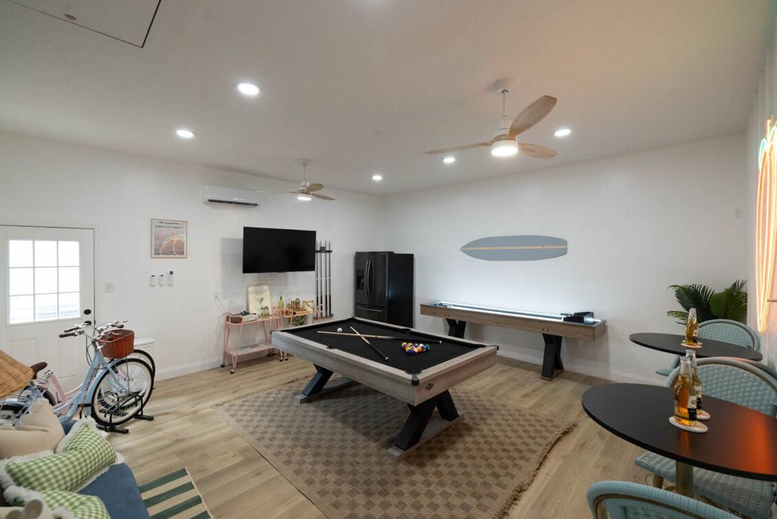 A living room with a pool table, a bicycle, a TV, and a pool table with a blue oval design on the wall.