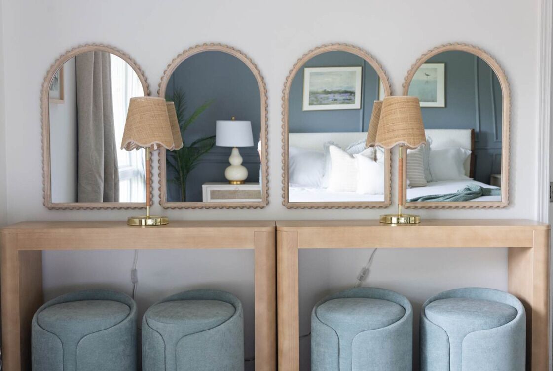 Une chambre à coucher avec deux tables de chevet, chacune équipée d’une lampe, un lit avec une literie blanche et un miroir au-dessus du lit.