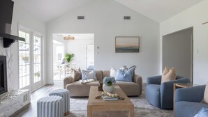 A spacious living room with a fireplace, a large sofa, ottomans, and a coffee table.