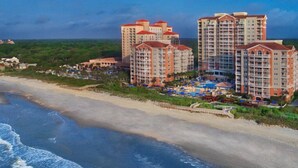A beachfront hotel with multiple high-rise buildings, a pool area, and a beach. - Oceanfront Charming 2-bedroom hotel in delightful Myrtle Beach (Myrtle Beach)