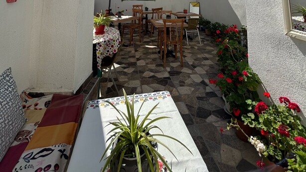 Un patio con una mesa, sillas, plantas en macetas y un paraguas amarillo.