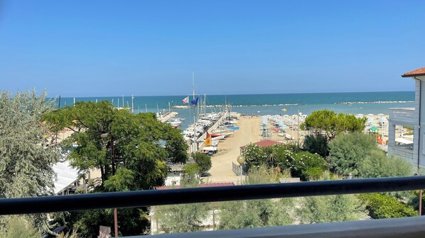 A coastal view with a marina, beach umbrellas, and boats.