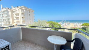 Un balcon donnant sur une plage, avec une table et une chaise.