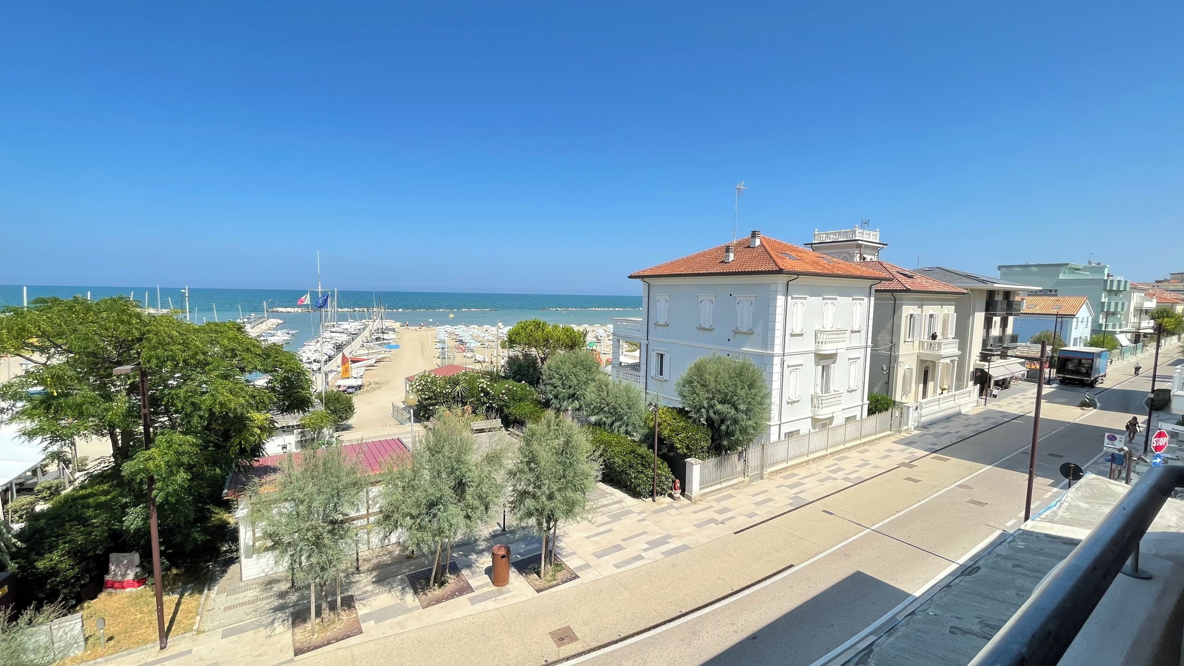 A coastal town with a marina, buildings, and a clear view of the sea.