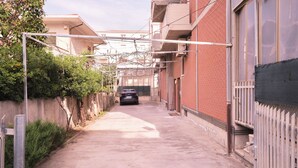 A narrow alleyway with a parked car, brick buildings, and a metal fence. - Porticciolo 3 vista mare x 4 persone (Viserba)