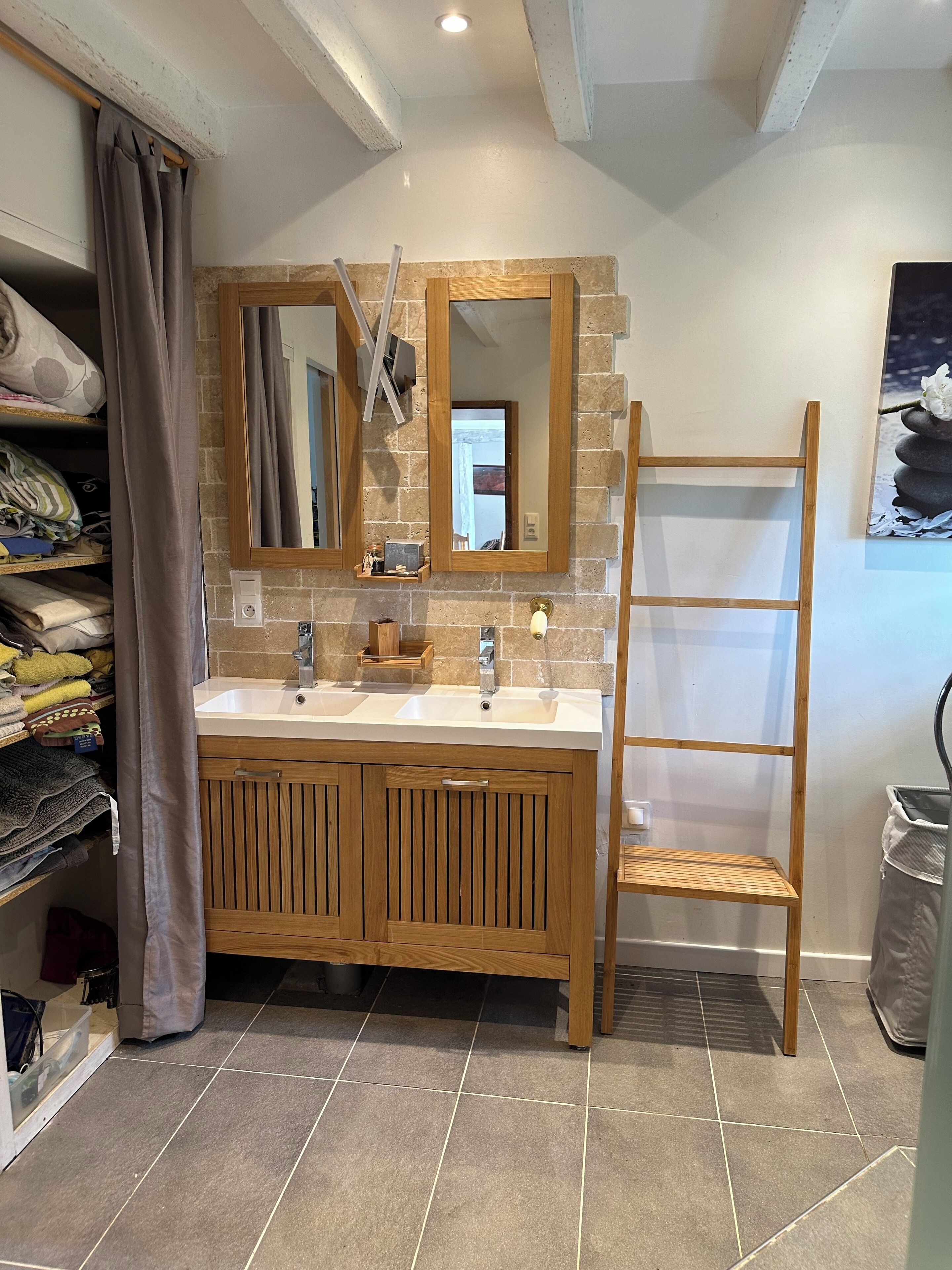 Une salle de bain avec un meuble-lavabo en bois, deux vasques, un miroir et un porte-serviettes.
