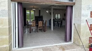 Un comedor con mesa y sillas, una cocina con estufa y encimera, y vistas al exterior a través de amplios ventanales.