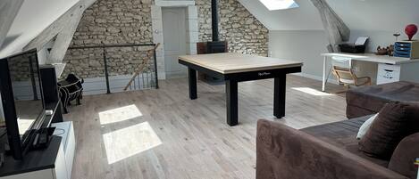 Un espacio tipo loft con pared de piedra, una mesa de madera, un sofá y un escritorio con computadora.