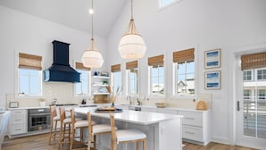 A spacious kitchen with a large island, wooden chairs, and pendant lighting. - Once Upon a Beach 204 COA (Port Aransas)